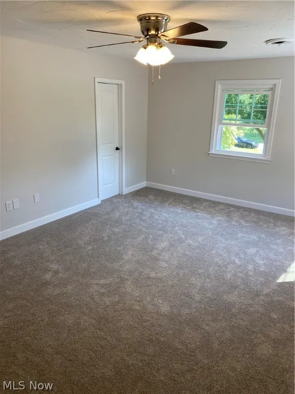 Carpeted spare room with ceiling fan