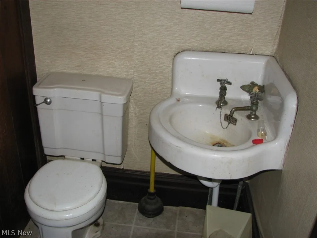 Downstairs half Bathroom featuring tile patterned floors, toilet, and sink