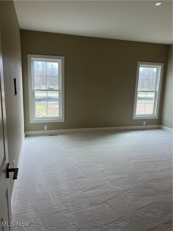 Carpeted spare room featuring baseboards