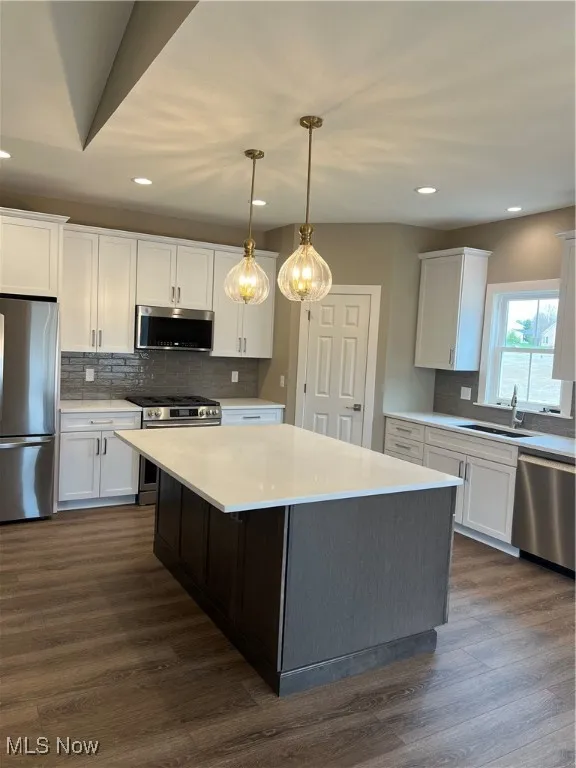 Kitchen featuring range, fridge, dishwashing machine, white cabinetry, and decorative backsplash