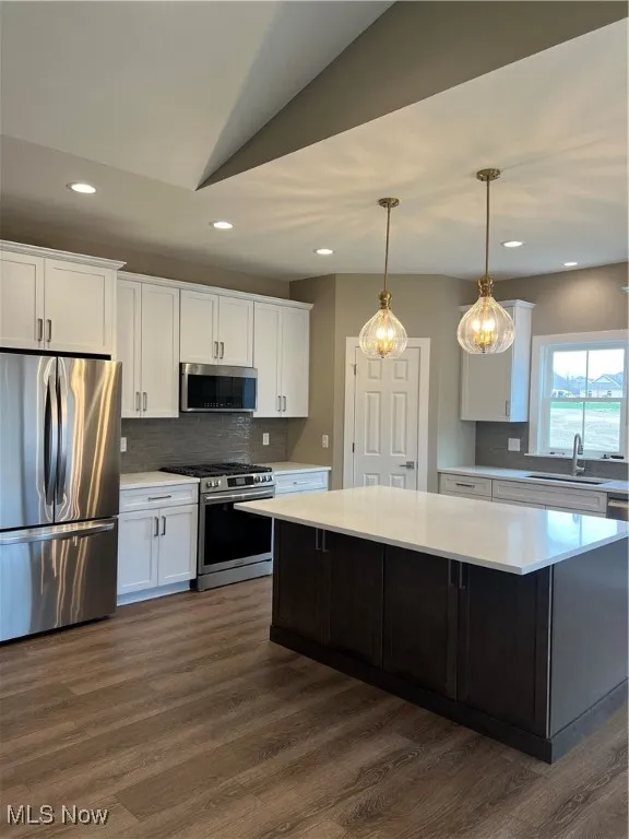 Kitchen with fridge, range, light countertops, white cabinetry, and tasteful backsplash