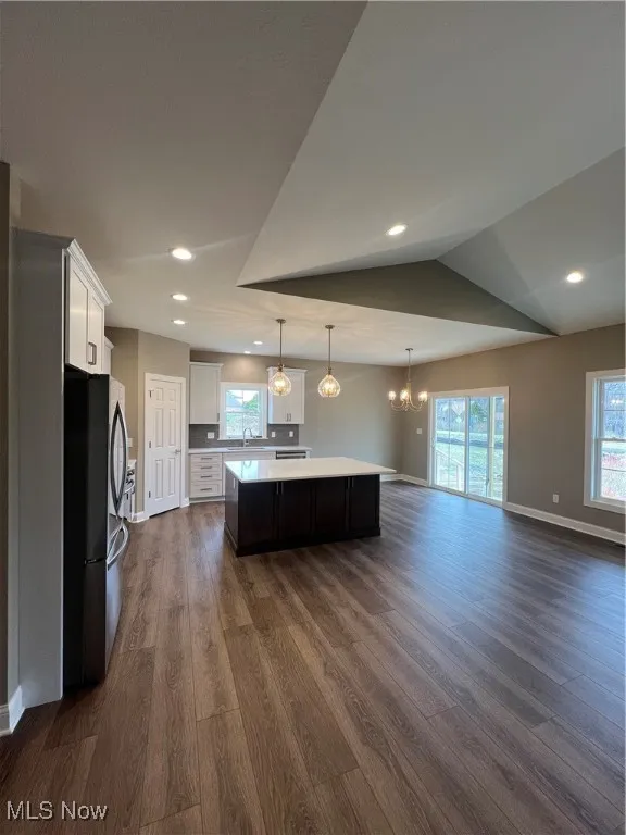 Kitchen featuring a kitchen island, a chandelier, light countertops, dark wood finished floors, and refrigerator