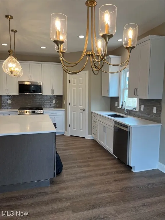 Kitchen with dishwasher, a chandelier, white cabinets, and recessed lighting