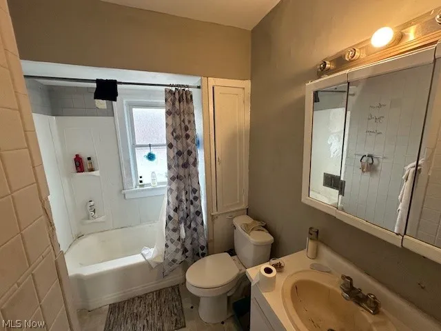 Full bathroom with vanity, shower / bath combo with shower curtain, tile patterned flooring, and toilet