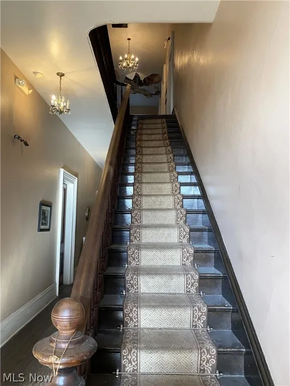 Stairway featuring banister, chandeliers and wood floors.