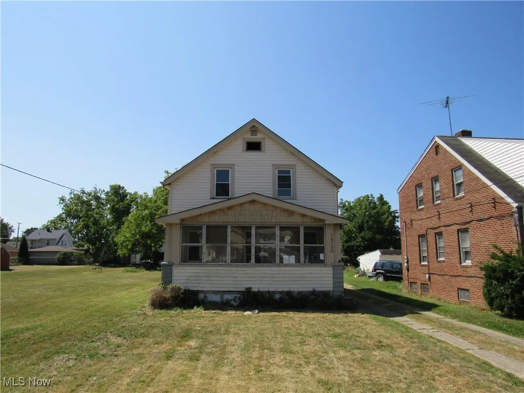 Rear view of house featuring a lawn and a sunroom
