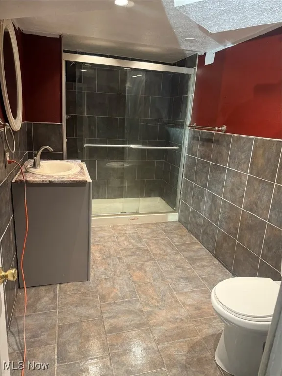 Bathroom with tile walls, vanity, and a shower stall
