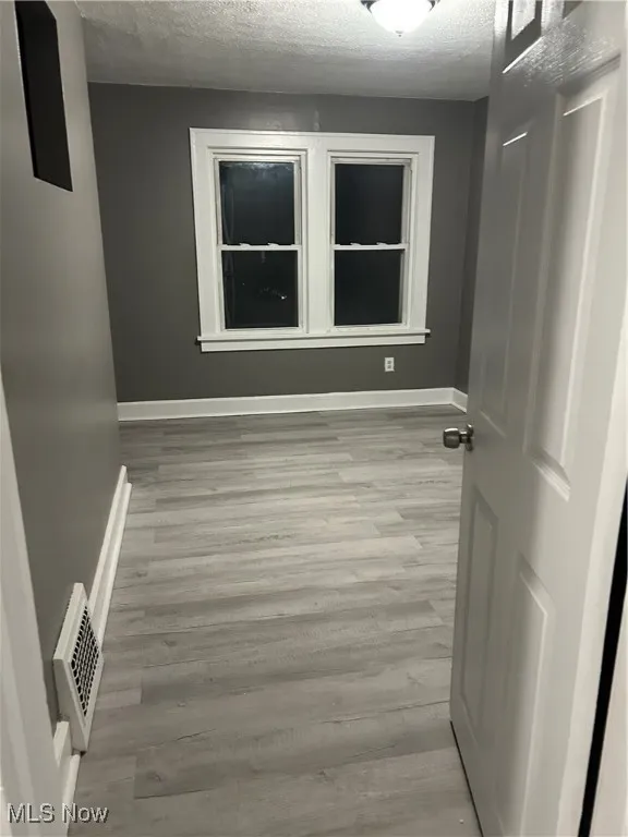 Empty room with a textured ceiling and wood finished floors