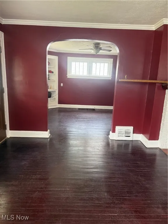 Spare room with arched walkways, ceiling fan, hardwood / wood-style flooring, and ornamental molding