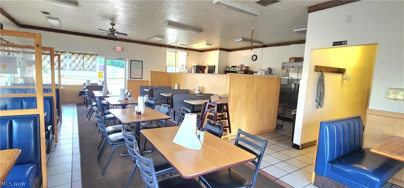 Dining space featuring ceiling fan, ornamental molding, light tile patterned floors, and a textured ceiling