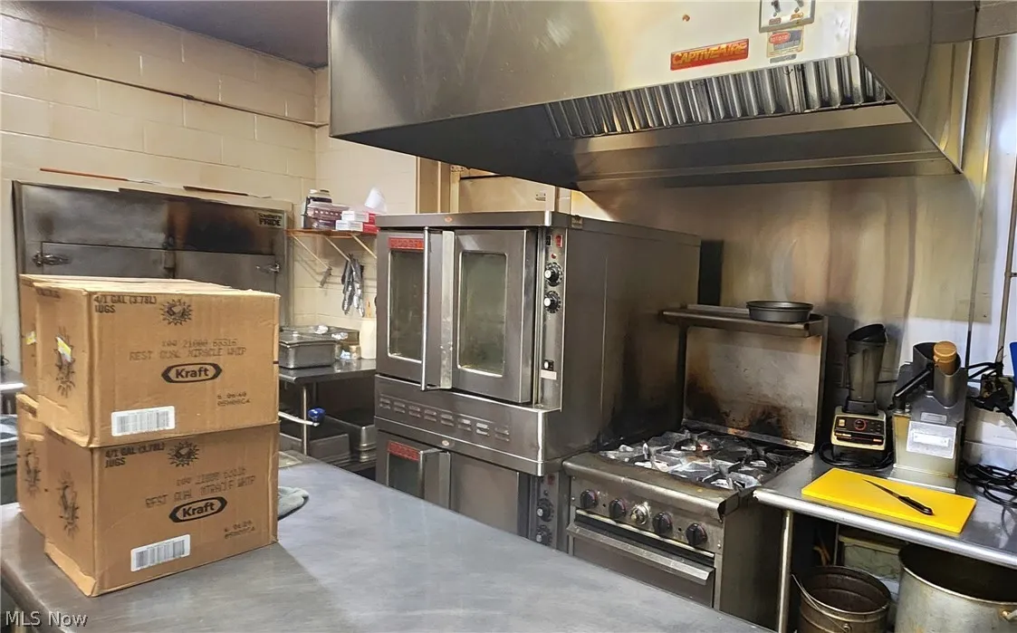 Kitchen with wall chimney range hood and concrete floors