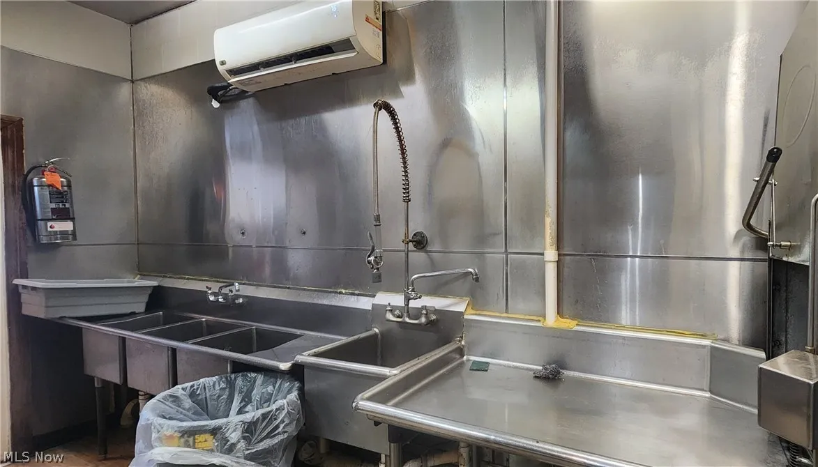 Kitchen featuring a wall unit AC, sink, and stainless steel counters