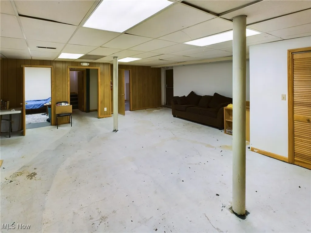 Basement featuring wooden walls and a paneled ceiling