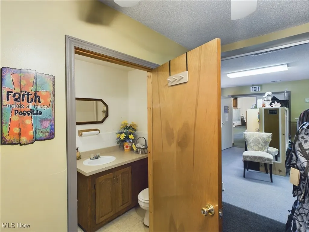 Bathroom featuring vanity, a textured ceiling, tile patterned flooring, and toilet