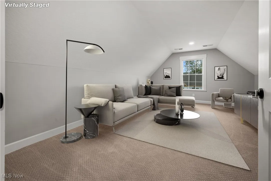 Carpeted living area featuring lofted ceiling and baseboards