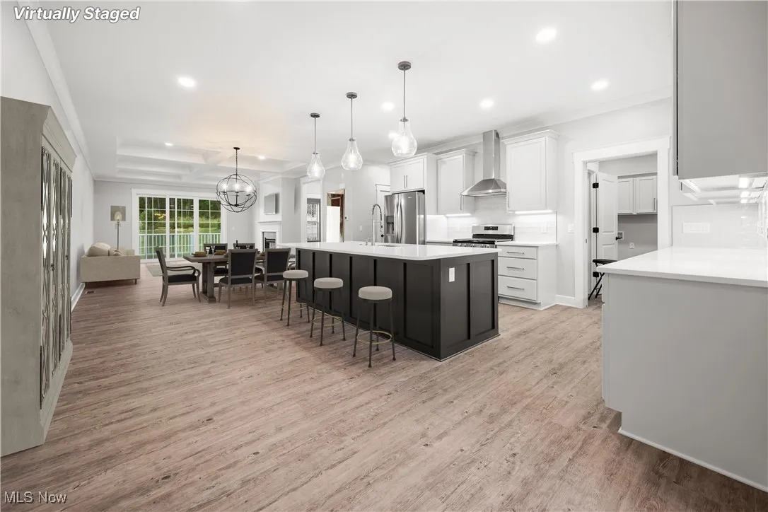 Kitchen featuring appliances with stainless steel finishes, recessed lighting, decorative backsplash, wall chimney range hood, and a kitchen breakfast bar
