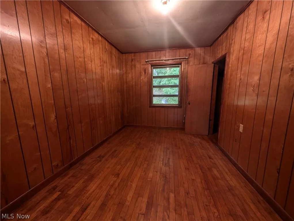 Empty room with dark wood-type flooring and wood walls