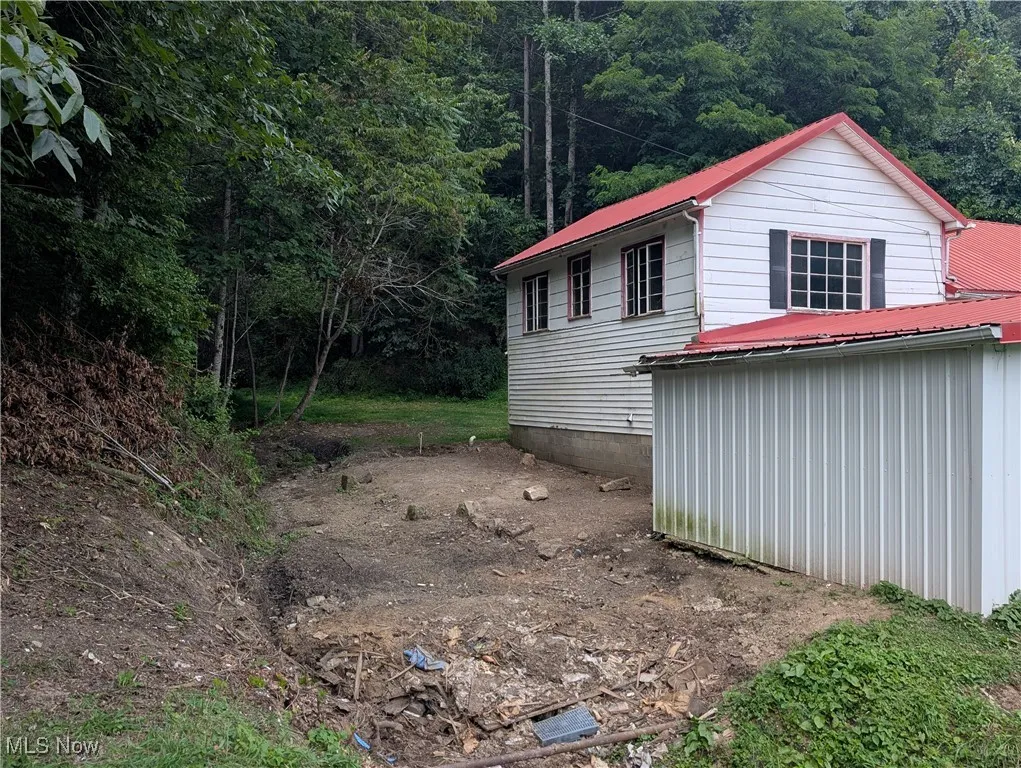 View of side of home with a metal roof and a forest view