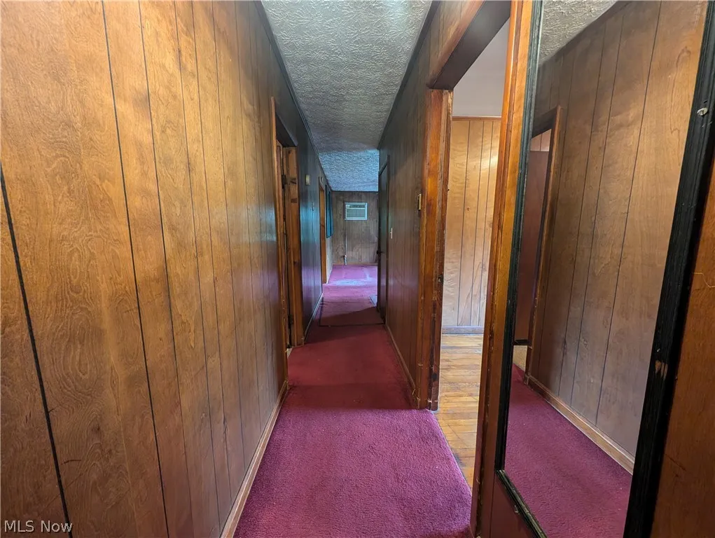 Corridor featuring carpet floors, wood walls, and a textured ceiling