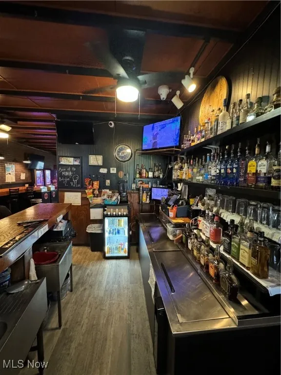 Bar with hardwood / wood-style floors and stainless steel counters