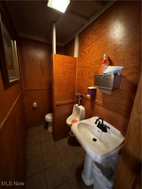 Bathroom with wooden walls, toilet, and tile patterned flooring