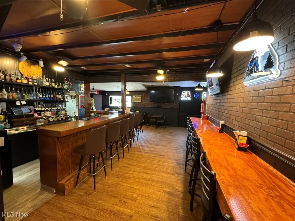 Bar with light hardwood / wood-style floors and brick wall