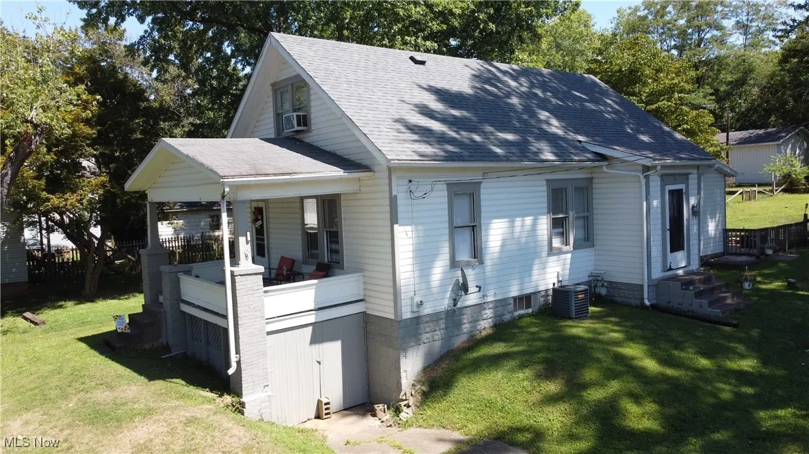 View of front facade featuring cooling unit and a front yard