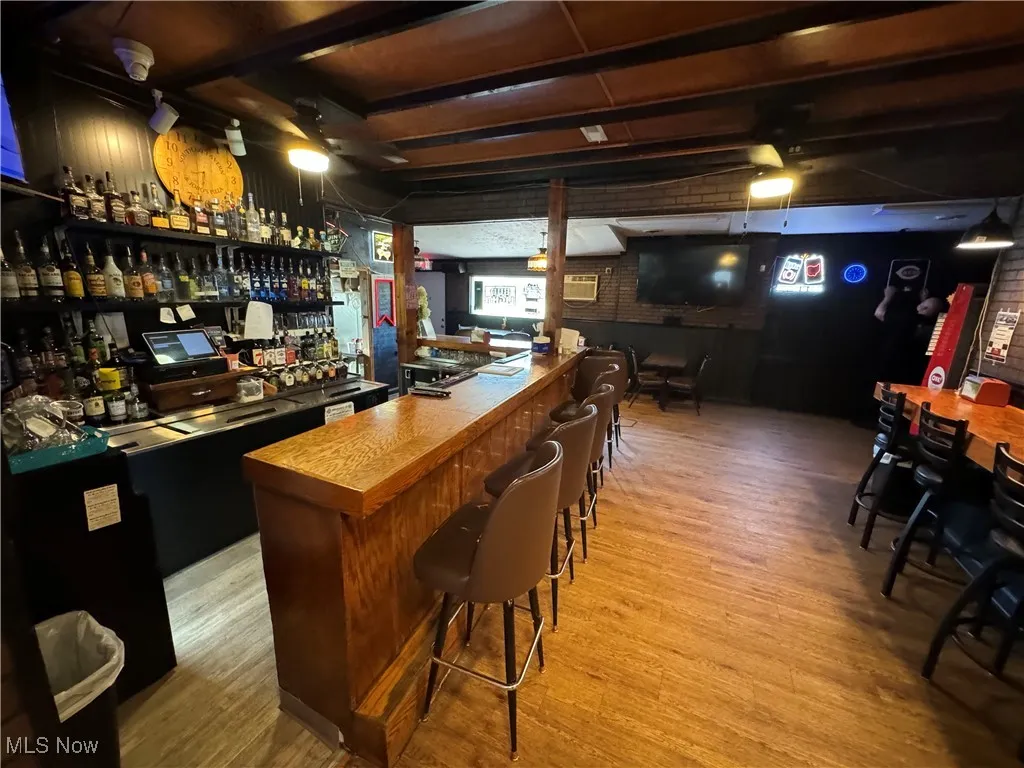 Bar featuring hardwood / wood-style floors and brick wall
