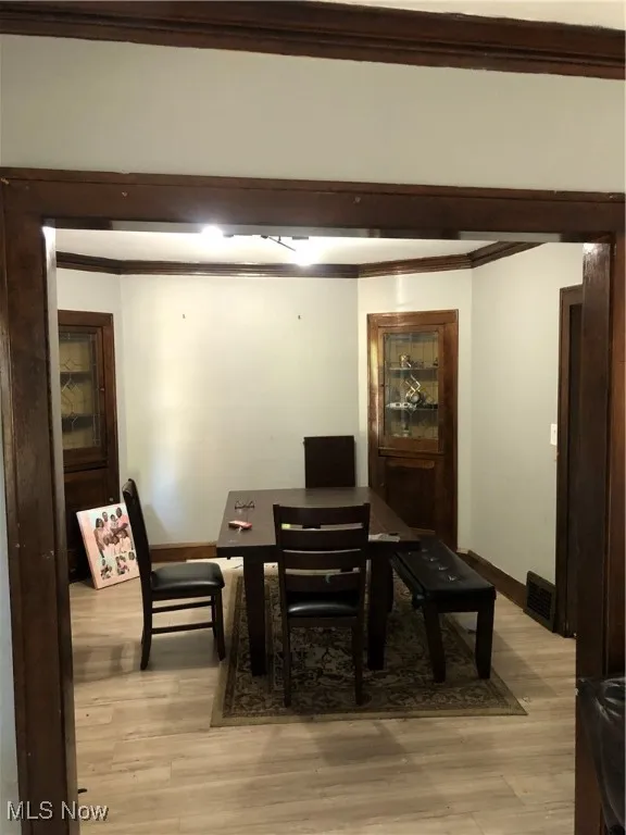 Dining area with crown molding and light wood-type flooring
