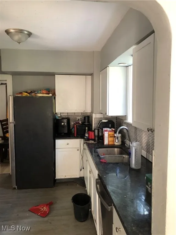 Kitchen featuring refrigerator, white cabinetry, sink, and dark wood-type flooring