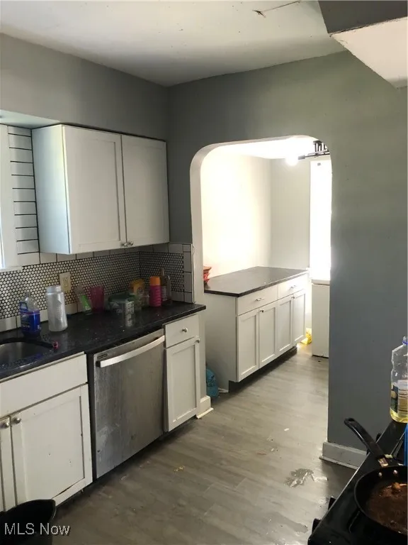 Kitchen with white cabinetry, dishwashing machine, decorative backsplash, wood-type flooring, and sink