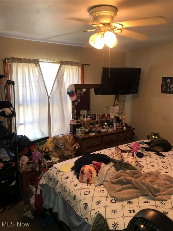 Carpeted bedroom featuring multiple windows and ceiling fan