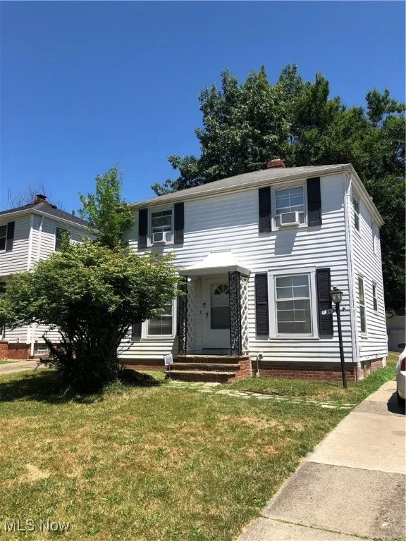 View of front facade featuring cooling unit and a front yard