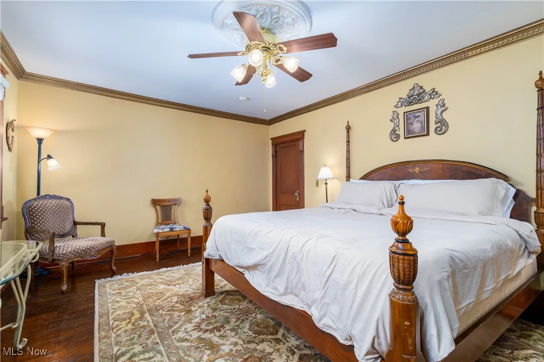 Bedroom with crown molding, dark wood-type flooring, and ceiling fan