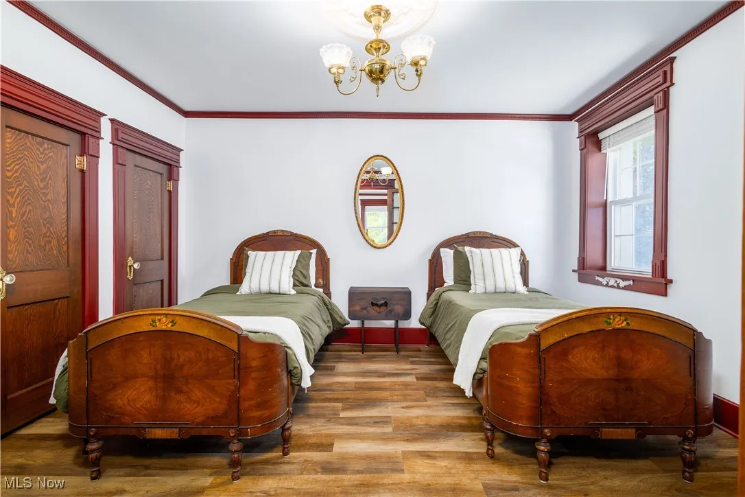 Bedroom featuring crown molding, a notable chandelier, and hardwood / wood-style floors