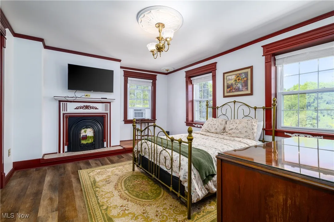 Bedroom featuring dark hardwood / wood-style floors, crown molding, and a chandelier