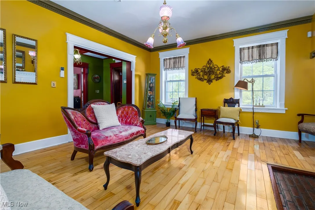 Living room with an inviting chandelier, ornamental molding, and hardwood / wood-style floors
