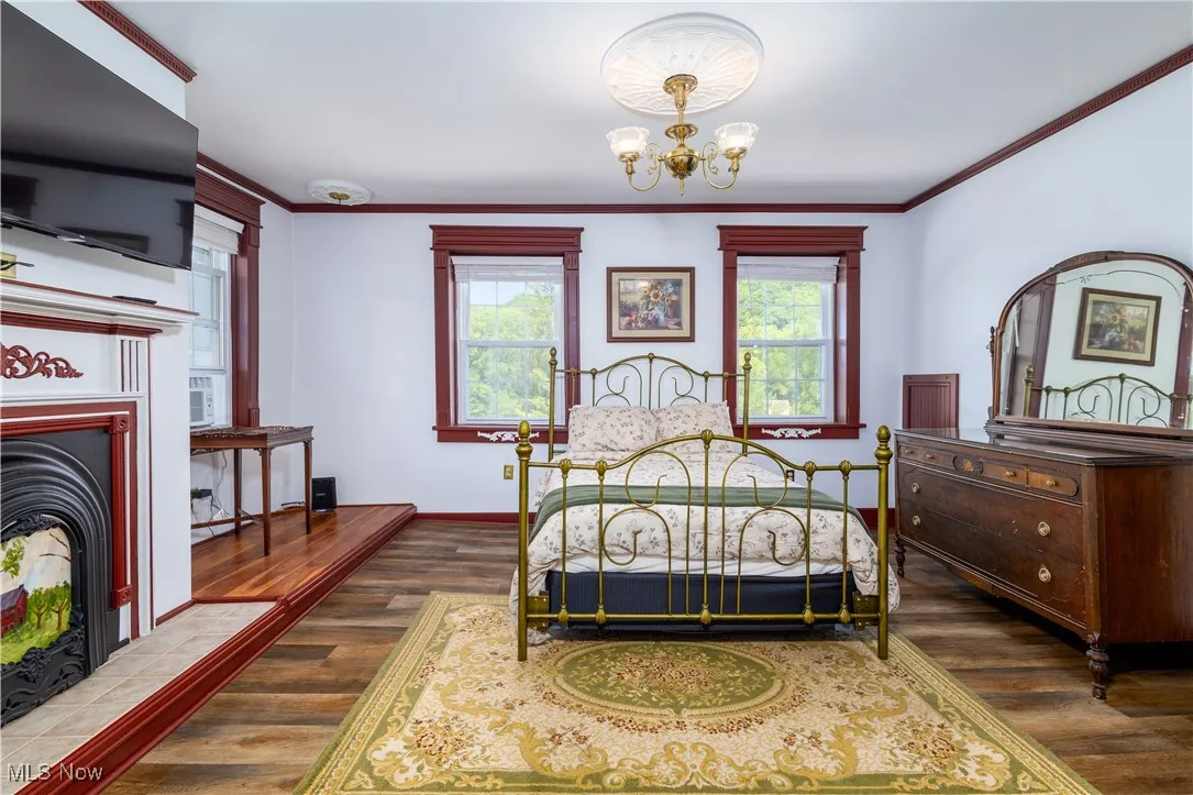Bedroom featuring an inviting chandelier, multiple windows, and dark hardwood / wood-style floors