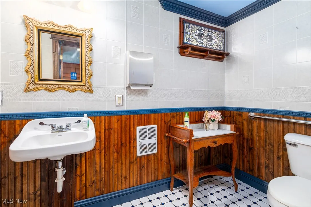 Bathroom with sink, toilet, tile patterned floors, and tile walls