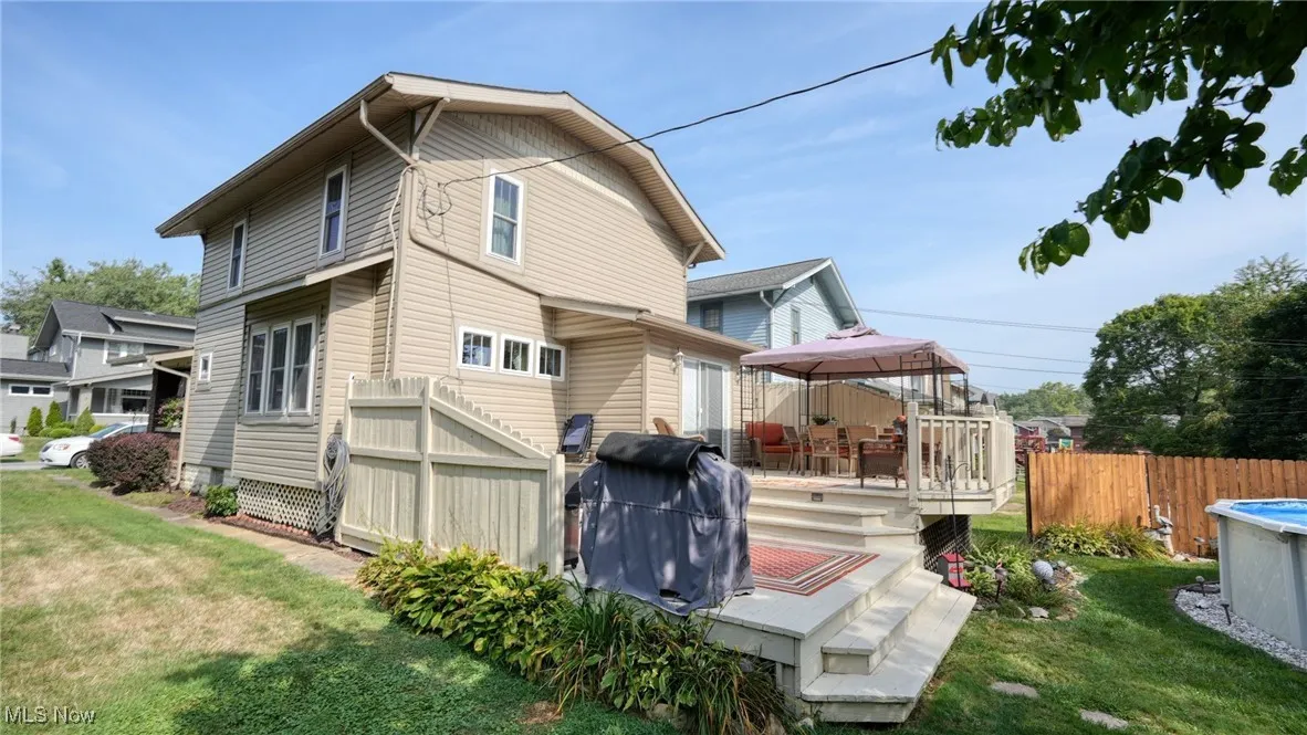 Rear view of house featuring a deck, a gazebo, and a lawn