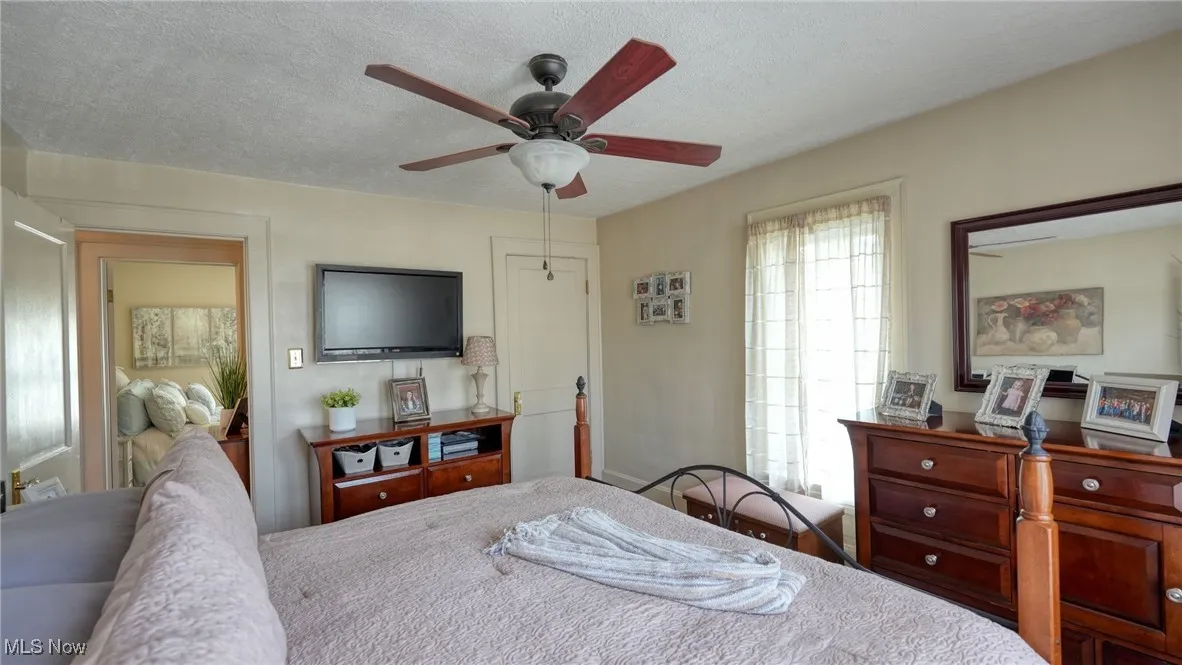 Bedroom with ceiling fan and a textured ceiling