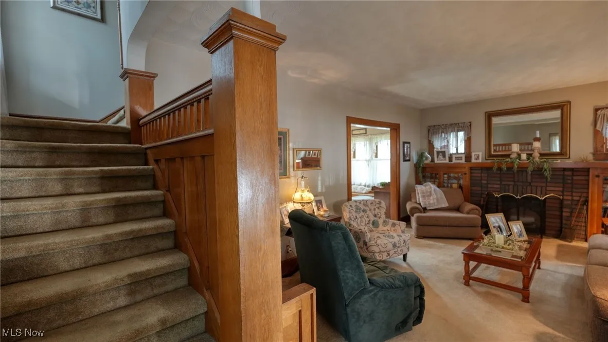 Living room with a fireplace, carpet, and ornate columns