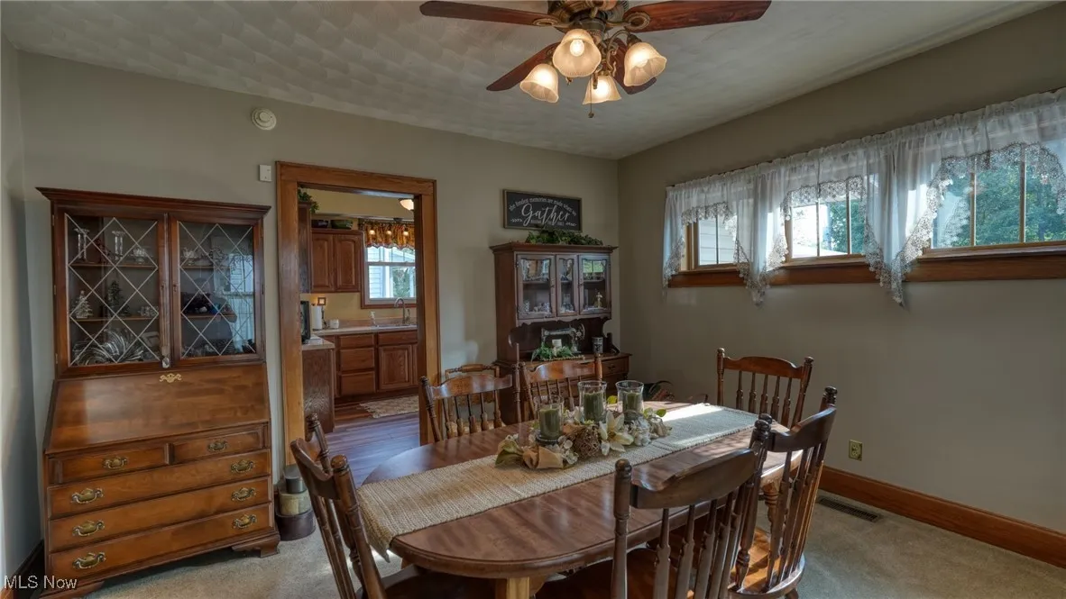Carpeted dining space with ceiling fan
