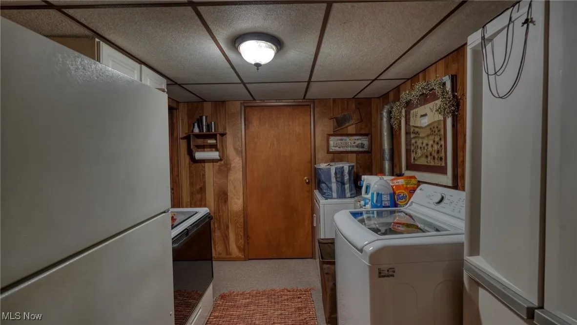 Washroom with wooden walls and washing machine and clothes dryer