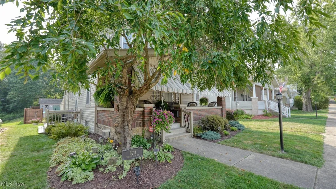 View of property hidden behind natural elements with a front yard