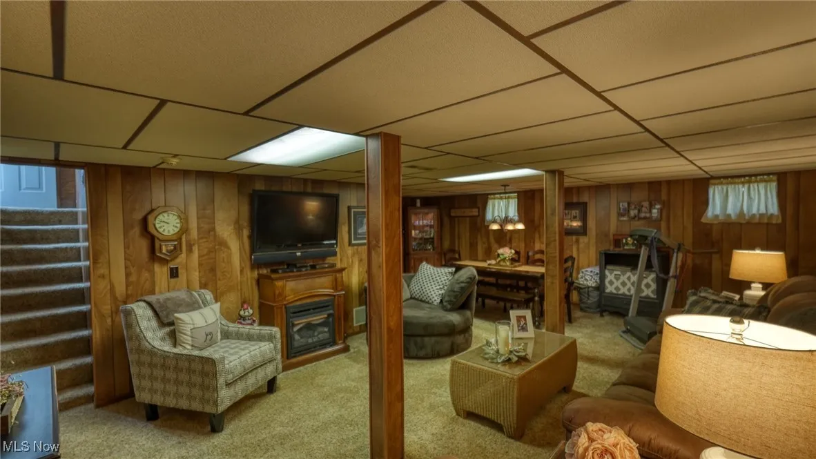 Carpeted living room with wood walls and a drop ceiling
