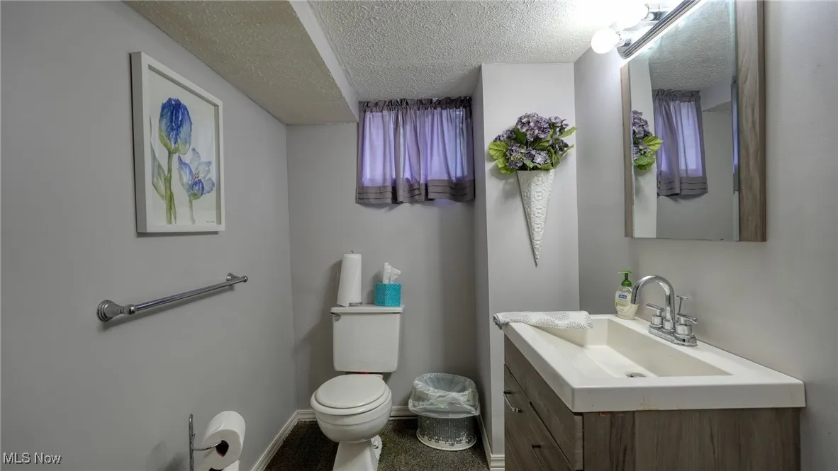 Bathroom featuring a textured ceiling, toilet, and vanity
