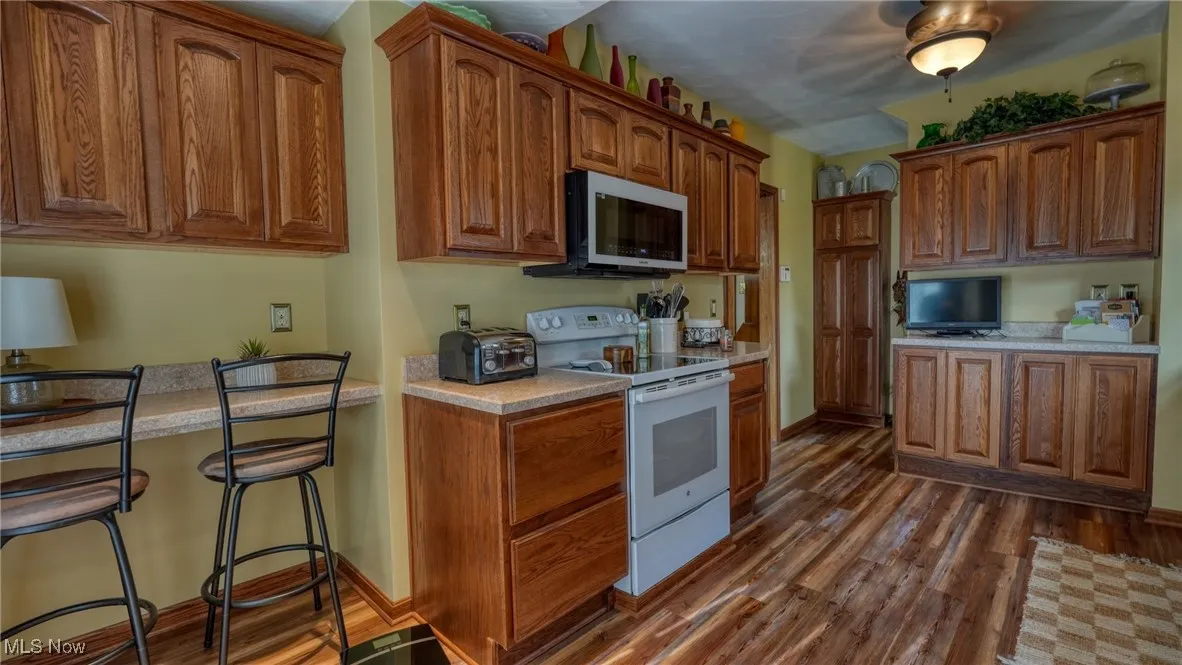 Kitchen featuring a kitchen bar, white electric range oven, and dark hardwood / wood-style flooring