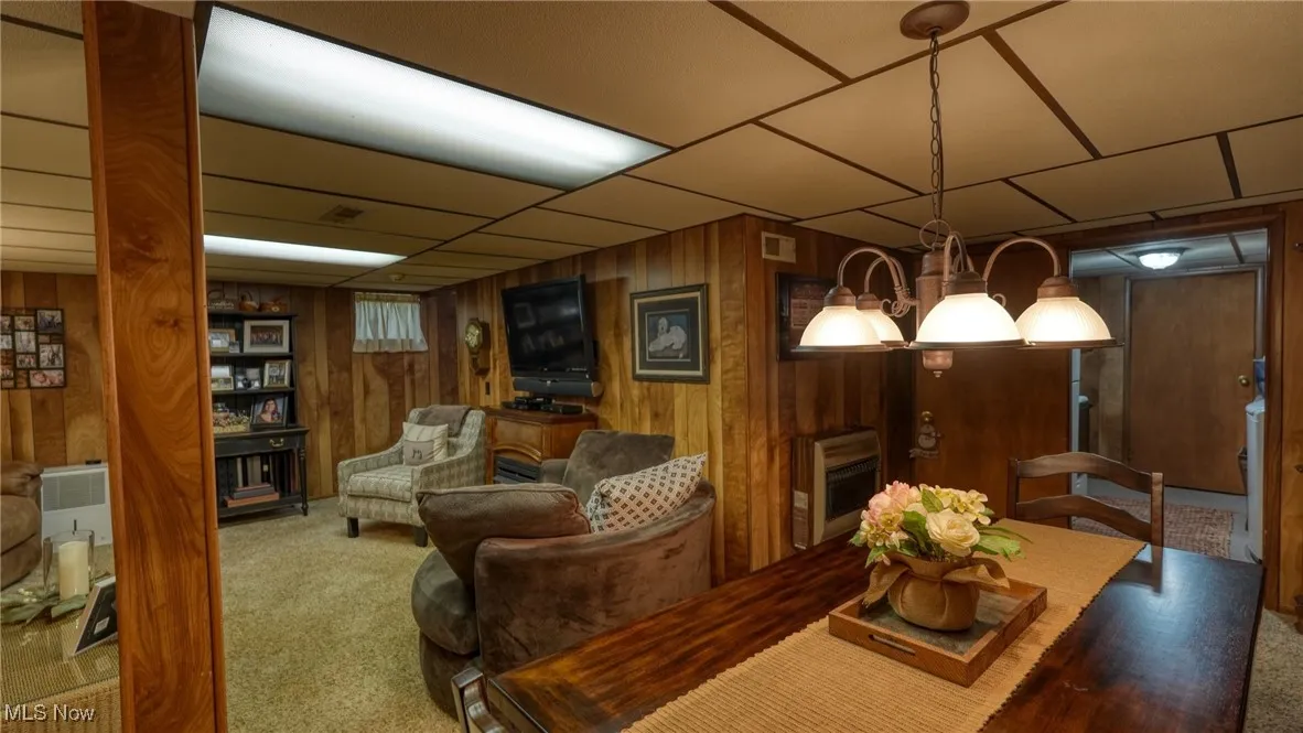 Living room featuring carpet, a paneled ceiling, and wooden walls
