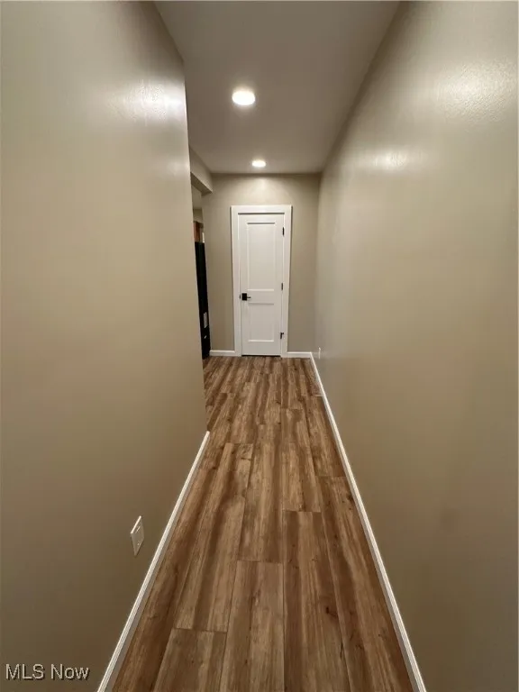 Hallway with hardwood / wood-style floors